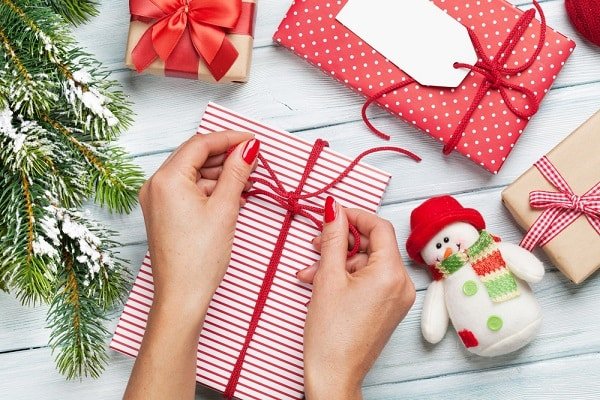 Female,Hands,Wrapping,Christmas,Gift,Box,Above,Wooden,Table.,Top